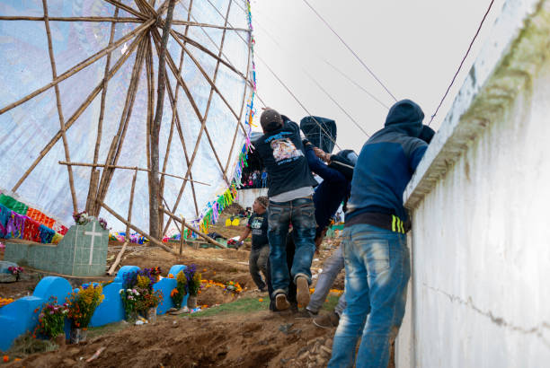 Group of men making giant kite in the cemetery to celebrate the day of the dead. 10/31/17, Santiago Sacatepequez, Guatemala - Group of men making giant kite in the cemetery to celebrate the day of the dead. all hallows by the tower stock pictures, royalty-free photos & images