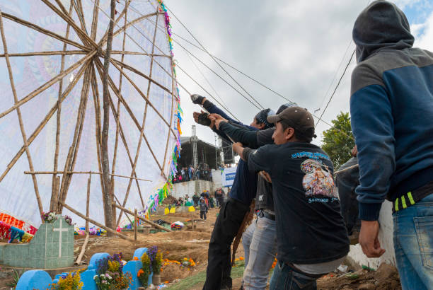 Group of men making giant kite in the cemetery to celebrate the day of the dead. 10/31/17, Santiago Sacatepequez, Guatemala - Group of men making giant kite in the cemetery to celebrate the day of the dead. all hallows by the tower stock pictures, royalty-free photos & images