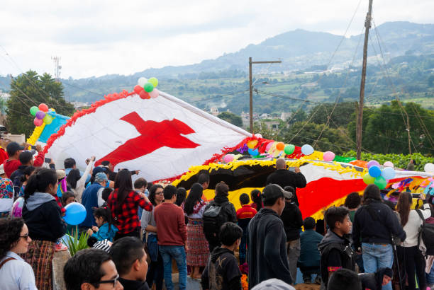 Group of men making giant kite in the cemetery to celebrate the day of the dead. 10/31/17, Santiago Sacatepequez, Guatemala - Group of men making giant kite in the cemetery to celebrate the day of the dead. all hallows by the tower stock pictures, royalty-free photos & images