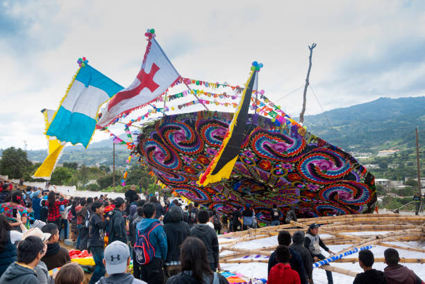 Group of men making giant kite in the cemetery to celebrate the day of the dead. 10/31/17, Santiago Sacatepequez, Guatemala - Group of men making giant kite in the cemetery to celebrate the day of the dead. all hallows by the tower stock pictures, royalty-free photos & images
