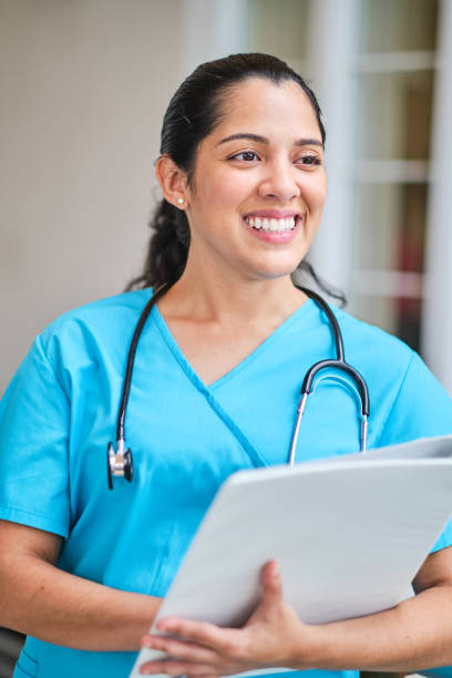 istock Young latin nurse with stethoscope holding a binder clip 1218308495