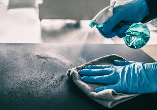 Surface sanitizing against COVID-19 outbreak. Home cleaning spraying antibacterial spray bottle disinfecting against coronavirus wearing nitrile gloves. Sanitize hospital surfaces prevention stock photo