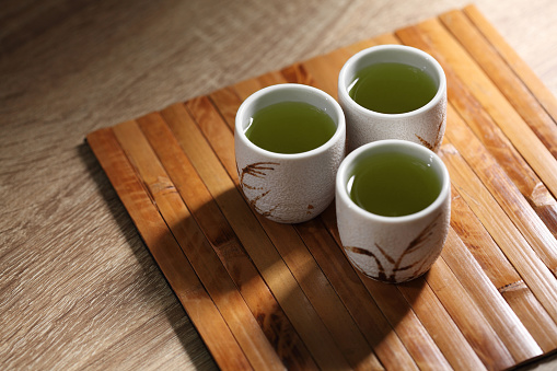 Japanese green tea in ceramic cup on wooden tray