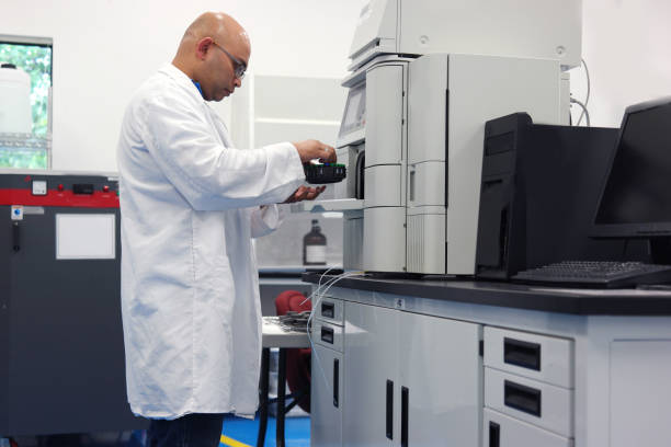 Scientist working with a HPLC Scientist working with a high pressure liquid chromatography machine drug manufacturing stock pictures, royalty-free photos & images