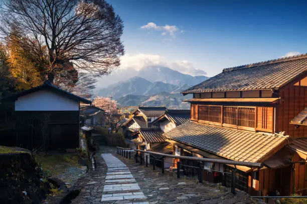 Magome juku downhill in Nakasendo with central alps mountain at sunrise, Kiso valley,  Nakatsugawa, Gifu, Japan. Famous travel landmark of preserved Japanese town with Wooden Building Facade in spring