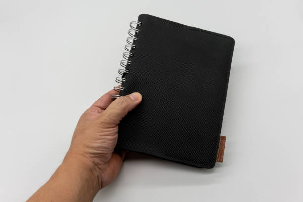 istock Hand holding black leather pocket notebook or sketchbook isolated on white background. 1218318137