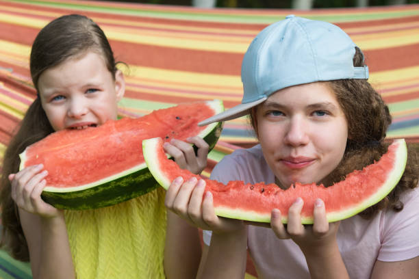 istock two girls eat red watermelon front view 1218318336
