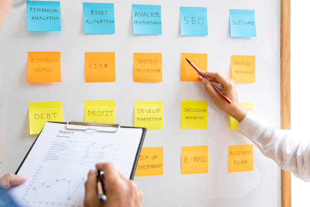 istock Business people arranging sticky notes commenting and brainstorming on work priorities colleague in a modern co-working space 1218322737