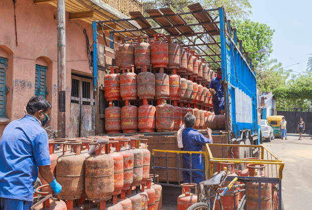 Supply of emergency items like LPG during lockdown in city. Near a gas godown, two delivery persons are engaged in unloading LPG gas cylinders from a lorry (semi-truck). Another person in uniform is putting those gas cylinders in a small delivery van used to deliver them to consumers.\n\nPhoto taken in Kolkata on 04/09/2020, 16th day of pan India lockdown.