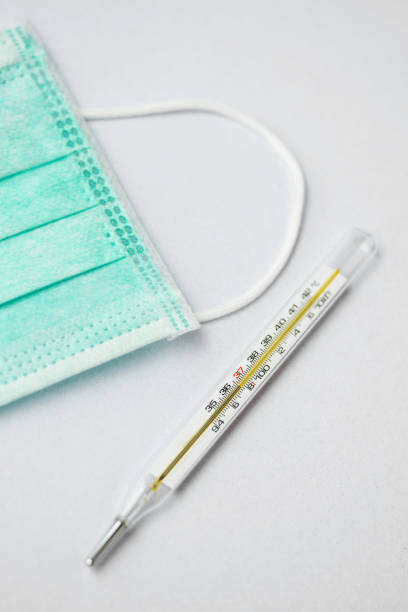 istock a mercury thermometer and a green face mask on white background 1218333222