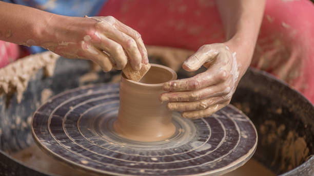 istock Workflow of a woman working behind a pottery wheel in an art workshop. Unknown master creates a jug. Focus only on the hands. Small business, talent, invention, hobby concept, inspiration. 1218334389