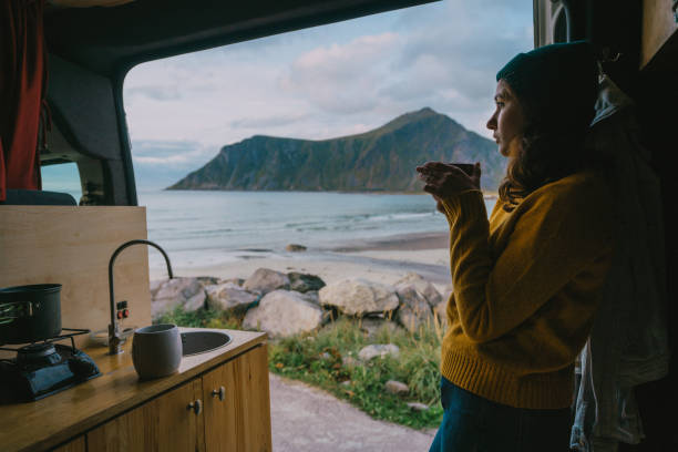 mujer bebiendo té en furgoneta camper con vista a la playa en la isla de lofoten - lofoten and vesteral islands beach nature norway fotografías e imágenes de stock