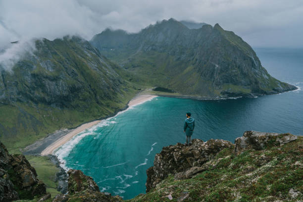 istock Man looking at Kvalvika beach while standing on rock 1218340518