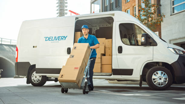 liefermann schiebt hand-lkw-trolley voll von kartons hände paket an einen kunden. courier liefert paket an den menschen im geschäftsviertel. - sackkarre stock-fotos und bilder