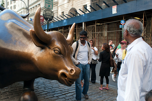 The Charging Bull Statue and the Fearless Girl Statue surrounded by tourists in the Financial District, near the New York Stock Exchange in Manhattan wreath by Arturo Di Modica, Bowling Green Park, New York