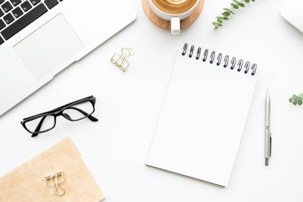 istock White office desk table with blank notebook, laptop computer, cup of latte coffee and supplies. Top view with copy space, flat lay. 1218344227