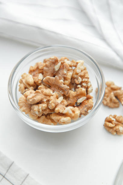 Peeled walnuts in a glass dish. A pile of walnuts on a white background. A pile of walnuts on a white background. Peeled walnuts in a glass dish. brain jar stock pictures, royalty-free photos & images