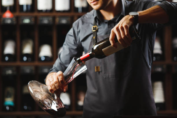 barkeeper gießt rotwein in transparentes gefäß im keller - decanter wine wineglass red wine stock-fotos und bilder