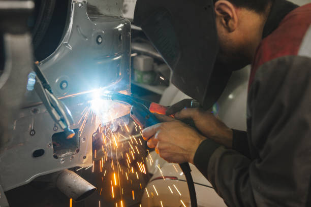 istock Worker in mask welds car in auto service of bodywork. 1218346689
