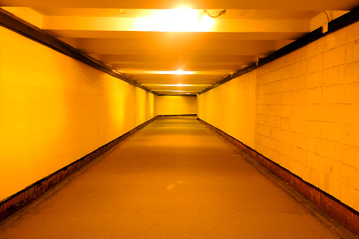a deserted underground pedestrian crossing lit by electric lamps