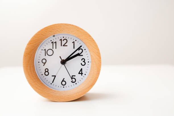 istock Wooden alarm clock on white table background 1218355697