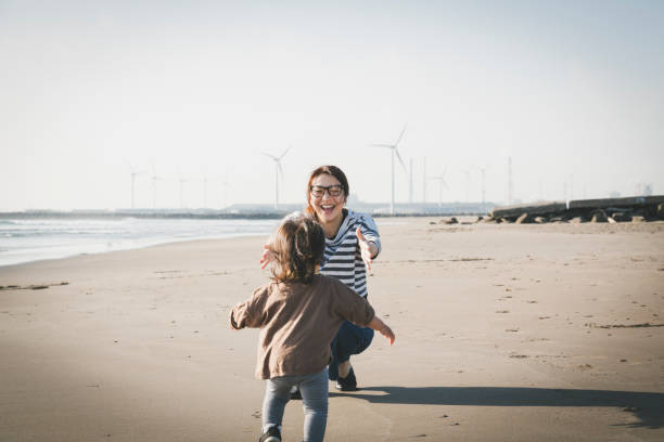 풍력 발전 단지 근처 해변에서 휴식을 취하는 어머니와 아기 - energy fuel and power generation wind turbine outdoors 뉴스 사진 이미지