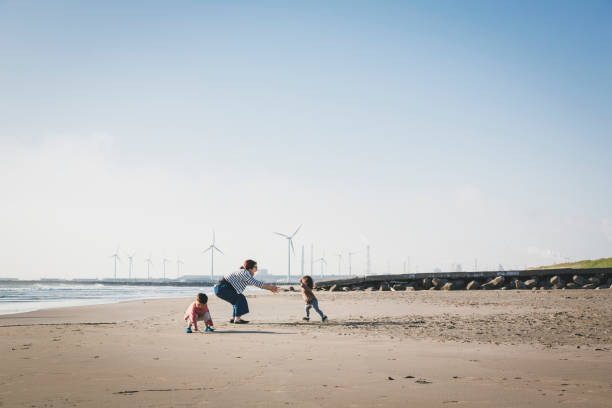 風力発電所に近いビーチでリラックスした家族 - 海岸 写真 ストックフォトと画像