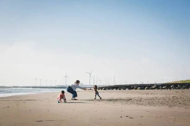 Photo of Family relaxed on the beach close to wind farm