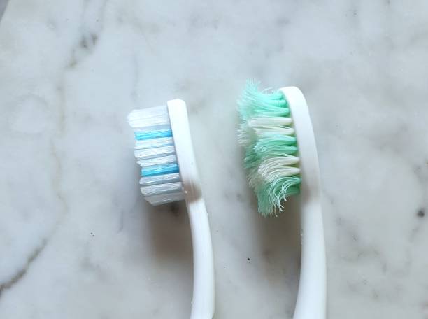 istock Profile view of two toothbrushes, one new and one used. Useful in comparison concepts, new vs old, used or brand new, before and after. Background texture for personal care, medical, healthy lifestyle 1218360562