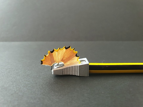 Lateral detail. Metal pencil sharpener, starting to sharpen a yellow and black pencil. Through the blade, the sharp wood appears.