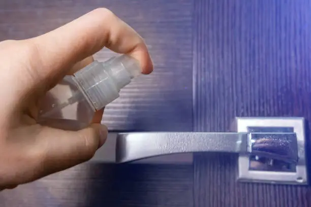 door handle with sanitizer liquid. Disinfect and remove virus from handle surface. Prevent spread of coronavirus.