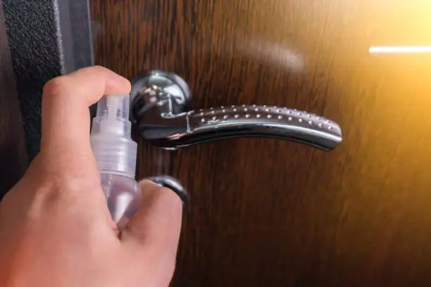 door handle with sanitizer liquid. Disinfect and remove virus from handle surface. Prevent spread of coronavirus.