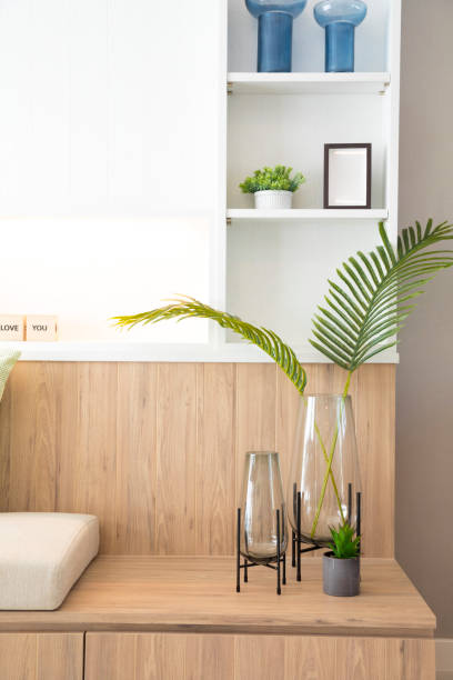 istock Artificial plant in glass vase compose on small wooden  table with shelf wall. 1218365412