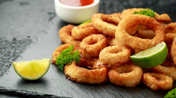 Oven baked breaded calamari rings served with lime wedges, sweet chilli sauce and mayonnaise Oven baked breaded calamari rings served with lime wedges, sweet chilli sauce and mayonnaise. fritter photos stock pictures, royalty-free photos & images