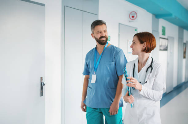 ritratto di uomo e donna medico che camminano in ospedale, parlano. - physicians assistant foto e immagini stock