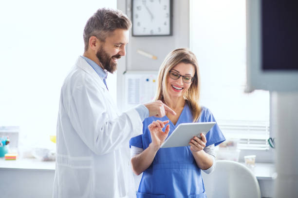 A dentist with dental assistant in modern dental surgery, working. A front view portrait of dental assistant and dentist in modern dental surgery, using tablet. tablet pc and digital hospital tools stock pictures, royalty-free photos & images