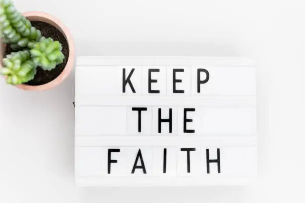 Photo of Keep the Faith, text written on a light box. Decorated with cactus.