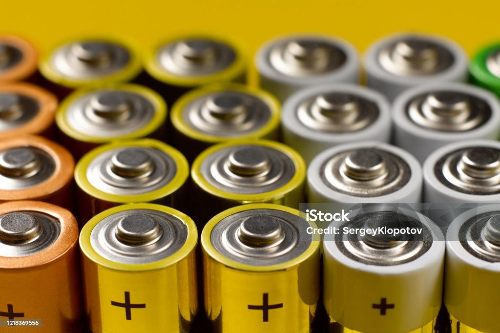 Closeup of a lot of color AA batteries Closeup of a lot of color AA batteries on a bright yellow background. Battery Stock Photo