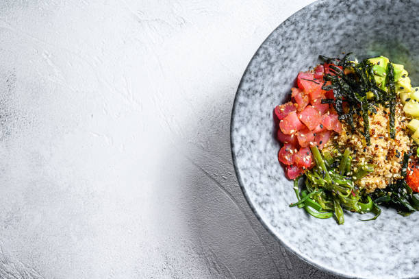 Tuna poke bowl with seaweed, avocado, cucumber, radish, sesame seeds. Gray background. Top view. Copy space