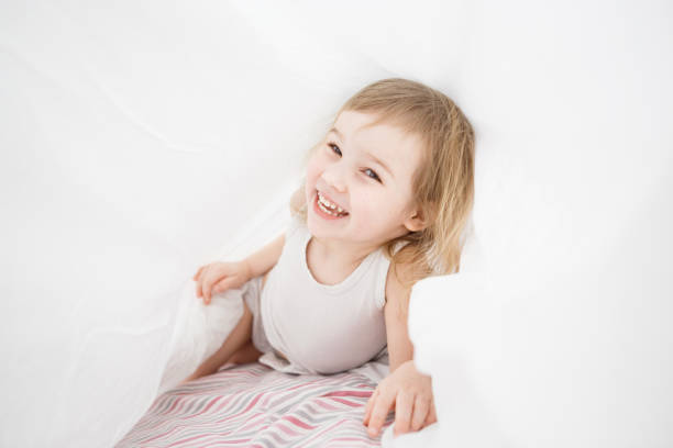 istock small girl have fun under blanket on bed. 1218371988