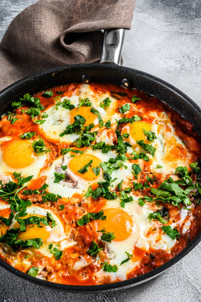 istock Breakfast with Fried eggs, tomatoes. Shakshuka in pan. Turkish  traditional dishes. Gray background. Top view 1218372602