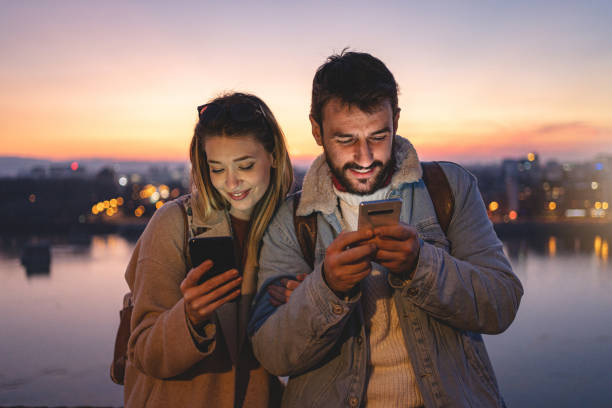 istock Serene couple using mobile phones while relaxing in sunset 1218373411