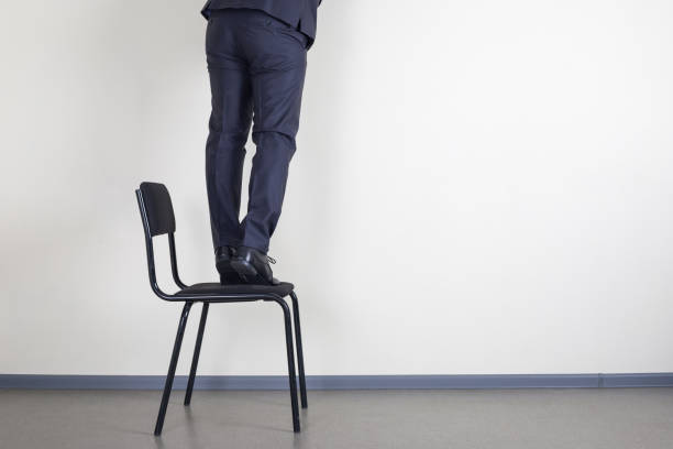 Feet of a businessman who climbed on an office chair stock photo