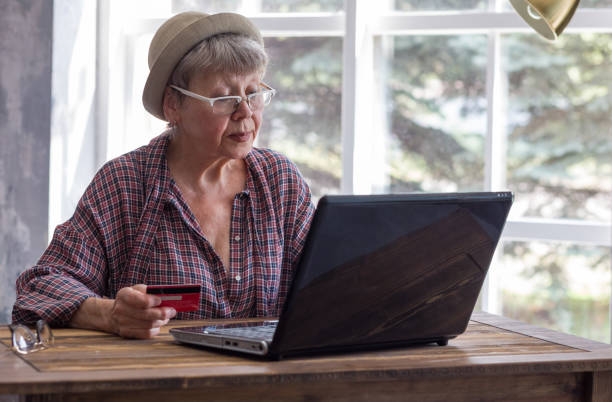 Elderly woman with computer and credit card inside. stock photo