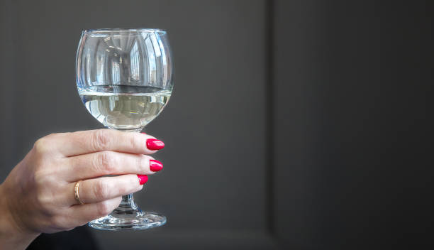 istock female hand holds a glass with white wine 1218377285