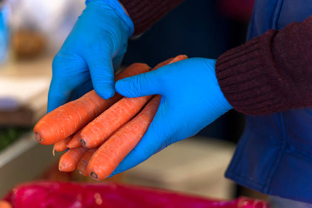 Greengrocer holding vegetables with rubber gloves during an epidemic of an infectious disease.