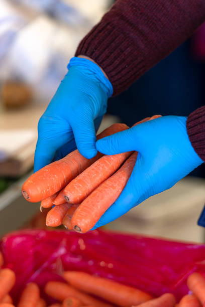 Greengrocer holding vegetables with rubber gloves during an epidemic of an infectious disease.