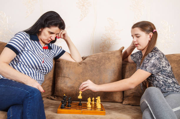 istock mom and daughter play chess at home 1218377643