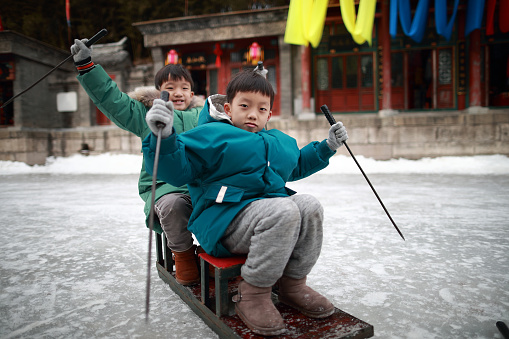 Child on the lake freezes to enjoy sledding, ice skate, ice bike at Summer Palace in Beijing in Winter,