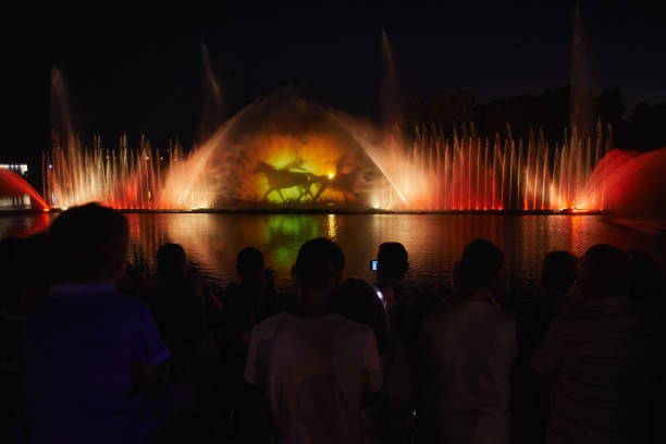 Lifestyles in Vinnytsia VINNYTSIA, UKRAINE - AUGUST 07, 2015: People look to a fountain, illuminated by a projector near the "Roshen" plant in the center of Vinnytsia. vinnytsia stock pictures, royalty-free photos & images